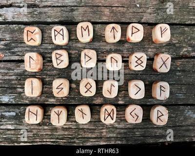 Una pila di rune in legno in foresta. Rune in legno giacciono su uno sfondo di legno vecchio. Rune sono tagliate da blocchi di legno. Su ciascun simbolo delle rune per fortuna Foto Stock