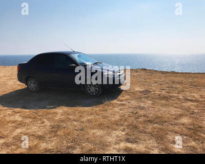 L'immagine nella parte anteriore della vettura sportiva scena alle spalle come il Sun andare giù con le turbine eoliche in retro Foto Stock