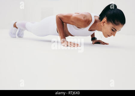 Vista laterale di una donna fitness facendo spingere ups. Donna in abiti fitness facendo fitness training. Foto Stock