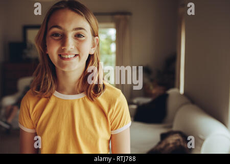 Ritratto di una ragazza sorridente in piedi a casa. Allegro ragazza con breve marrone capelli in piedi in camera sua. Foto Stock