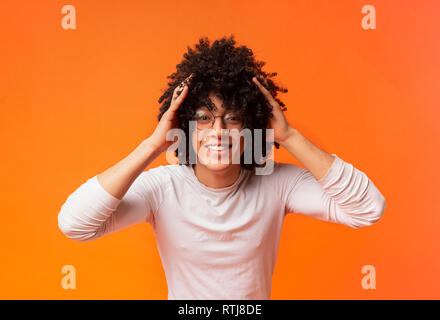 Sorpreso giovani curly-dai capelli ragazzo nero stringendo la sua testa, Foto Stock