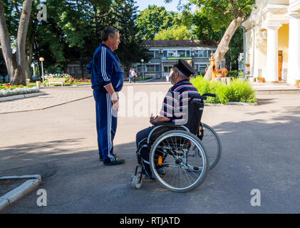 Voronezh, Russia - 20 agosto 2018: un uomo che parla con un anziano disabile in un parco della città Foto Stock