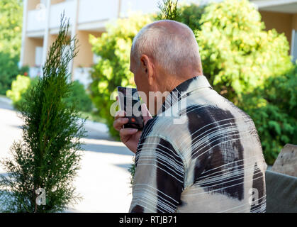 Voronezh, Russia - Agosto 20, 2018: uomo anziano parlando al telefono cellulare in vivavoce Foto Stock