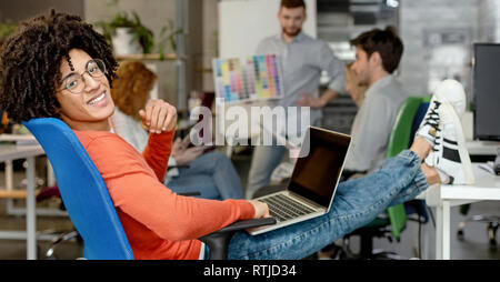 Uomo sorridente godendo di lavorare nel moderno e confortevole accogliente co-spazio di lavoro Foto Stock