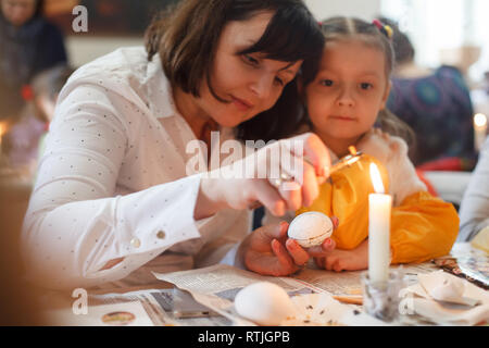 Lviv, Ucraina - 11 Marzo 2018. Mamma e figlia dipingere le uova di Pasqua al tavolo. Ucraino Uova di Pasqua atelier di pittura. Foto Stock