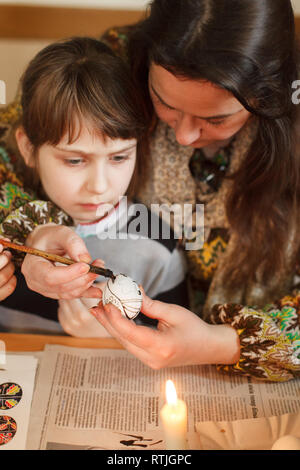 Lviv, Ucraina - 11 Marzo 2018. Mamma e figlia dipingere le uova di Pasqua al tavolo. Ucraino Uova di Pasqua atelier di pittura. Foto Stock