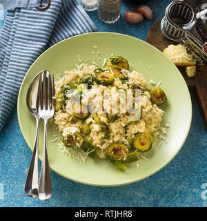 Italian spring risotto con cavolini di Bruxelles e il parmigiano reggiano sul tavolo. Cibo sano per tutta la famiglia, partito o il menu del ristorante e il rosso win Foto Stock