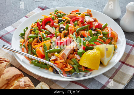 In stile messicano sani con insalata verde fagiolo, peperoni, olive nere, carota, mais e prosciutto tagliato in strisce su una piastra bianca su una tabella di calcestruzzo con Foto Stock