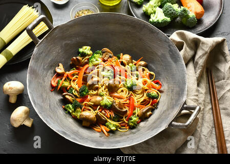 Udon friggere gli spaghetti con le verdure nel wok padella in pietra nera tabella. Mescolare le verdure fritte con tagliatelle in stile asiatico. Foto Stock