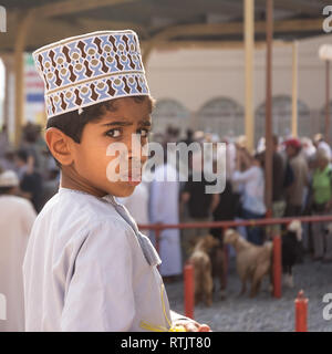 Nizwa, Oman - 2 Novembre 2018: Ritratto di bambino girando attorno sorpreso dalla telecamera al venerdì sul mercato degli animali in Nizwa Foto Stock