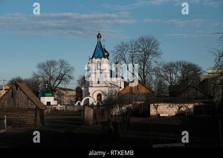 Vista del 18th secolo Santa Trasfigurazione Chiesa costruita in stile russo retrospettivo è visto attraverso tipiche case di legno a Motol o Motal una città in Ivanava Raion della regione di Brest, che era una volta casa di una grande comunità ebraica e fu annientato dai tedeschi durante Il Secondo Guerra Mondiale. Bielorussia Foto Stock