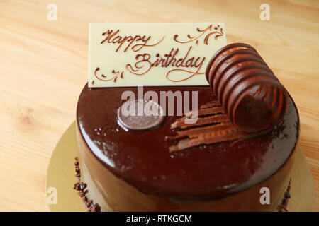 Bianco crema cioccolato compleanno biglietto di auguri e rabboccato su mousse al cioccolato torta sul tavolo di legno Foto Stock