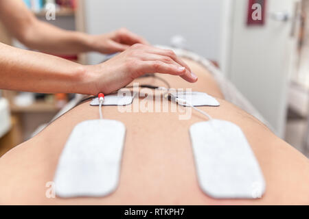 Fisioterapista applicazione degli elettrodi ad un paziente Foto Stock