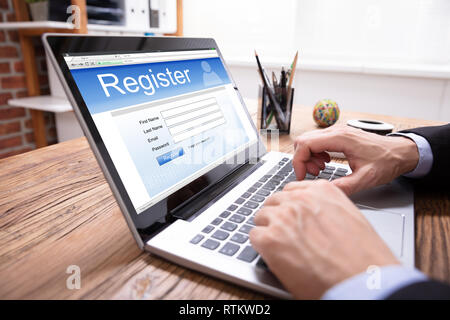 Imprenditore il deposito a mano modulo di registrazione online su Laptop Foto Stock