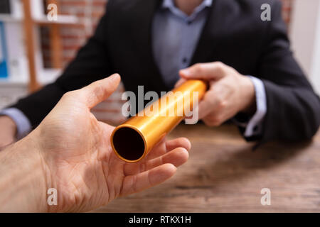 Close-up di un imprenditore il passaggio di mano del relè d'oro testimone al suo Partner Foto Stock