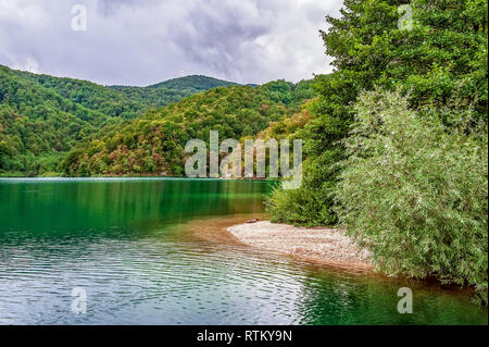 Uno dei molti di più incredibili laghi di Plitvice, Croazia. Lonely barca bianca al tramonto. Una vera vergine e meraviglioso pezzo di natura. Foto Stock