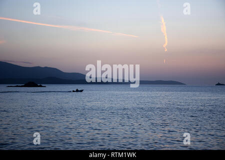 Piccola imbarcazione galleggia in mare, con vista a Korfu isola. Tramonto sulla spiaggia in Ksamil vicino Saranda, Albania. Foto Stock