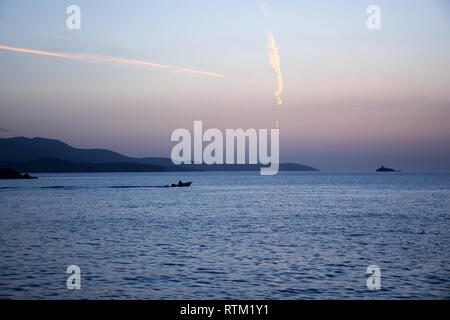 Piccola imbarcazione galleggia in mare, con vista a Korfu isola. Tramonto sulla spiaggia in Ksamil vicino Saranda, Albania. Foto Stock