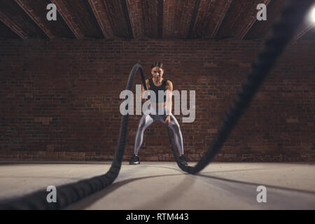 Il duro lavoro di crossfit femmina istruttore dimostra che la formazione delle corde sono molto allenamento dinamico che accelera l'atleta di impulso mentre il rafforzamento del suo Foto Stock