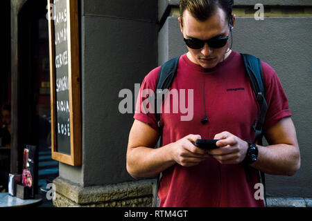 Barcellona, Spagna - Nov 12, 2017: giovane con occhiali da sole e zainetto utilizzando il telefono dello smartphone in strada a Barcellona Foto Stock