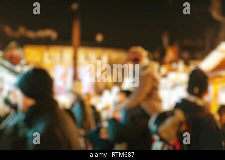 Illuminata fiera di Natale mercato kiosk di stallo con la gente a piedi ammirando acquisto di regali e cibi tradizionali Foto Stock