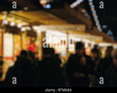 Illuminata fiera di Natale chiosco di stallo di mercato con un sacco di bei segni artigianale fatta in casa di crepes e cibo dolce la gente camminare Foto Stock