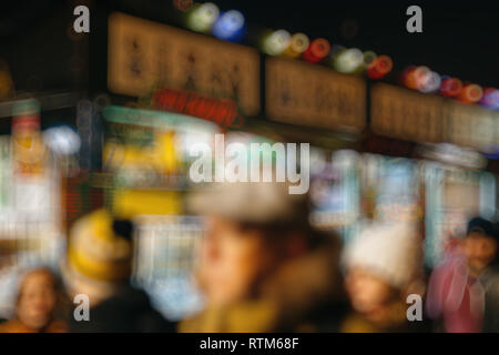 Illuminata fiera di Natale mercato kiosk di stallo con carichi di bootles con vin chaud - vin brulé e i clienti in attesa in coda Foto Stock