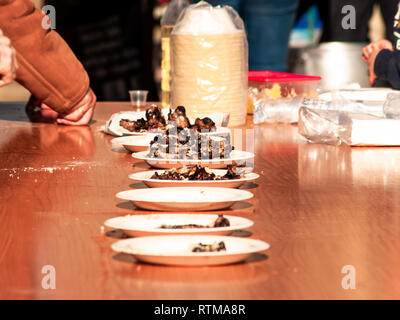 Irriconoscibile la persona che ha preso la carne cotta da un piatto di carta in strada a un partito popolare in un villaggio in Spagna Foto Stock