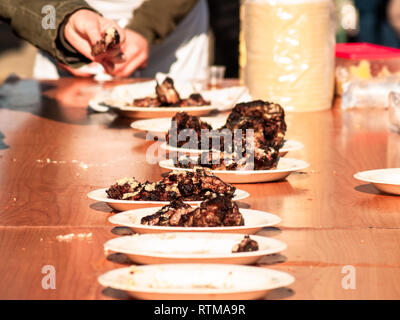 Irriconoscibile la persona che ha preso la carne cotta da un piatto di carta in strada a un partito popolare in un villaggio in Spagna Foto Stock