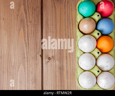 Colorate le uova di Pasqua nella casella su sfondo di legno con copia spazio. Foto Stock