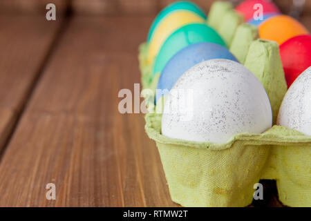 Colorate le uova di Pasqua nella casella su sfondo di legno con copia spazio. Foto Stock