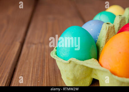 Colorate le uova di Pasqua nella casella su sfondo di legno con copia spazio. Foto Stock