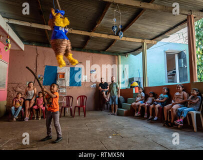 Giovane ragazzo latino swinging a pinata a Guatemala festa di compleanno Foto Stock