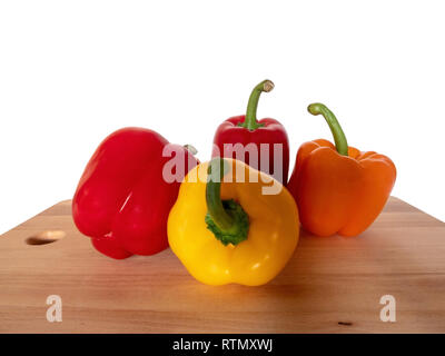 Quattro colorati in modo diverso i peperoni su una tavola di legno di fronte a uno sfondo bianco Foto Stock