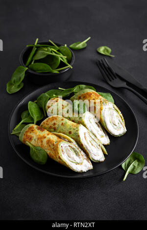 Crepes salate con spinaci e formaggio feta su sfondo nero Foto Stock