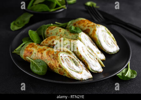 Crepes salate con spinaci e formaggio feta su sfondo nero Foto Stock