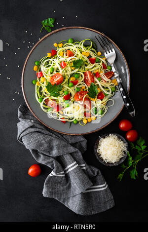 Zoodlie, sano cibo vegan - zucchine noodlie con fresco verde piselli, pomodoro, peperone e mais per il pranzo, vista da sopra Foto Stock