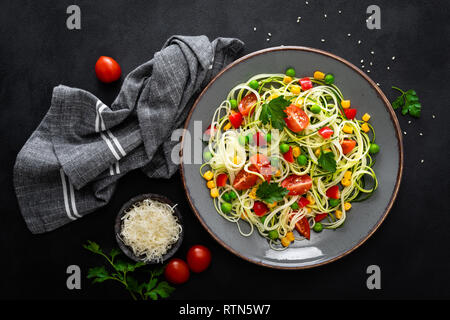 Zoodlie, sano cibo vegan - zucchine noodlie con fresco verde piselli, pomodoro, peperone e mais per il pranzo, vista da sopra Foto Stock