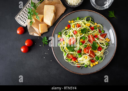 Zoodlie, sano cibo vegan - zucchine noodlie con fresco verde piselli, pomodoro, peperone e mais per il pranzo, vista da sopra Foto Stock