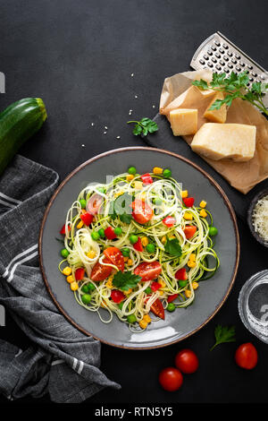 Zoodlie, sano cibo vegan - zucchine noodlie con fresco verde piselli, pomodoro, peperone e mais per il pranzo, vista da sopra Foto Stock