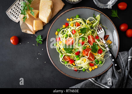 Zoodlie, sano cibo vegan - zucchine noodlie con fresco verde piselli, pomodoro, peperone e mais per il pranzo, vista da sopra Foto Stock