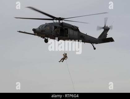 Stati Uniti Air Force Staff Sgt. Coin Monge 58th Rescue Squadron (RQS) Pararescueman, respinge al di fuori di un HH-60 elicottero Pavehawk assegnato al sessantesimo RQS presso la Air Force prove alla cerimonia di apertura per la Base Aerea Militare di Nellis Nev., 1 marzo 2019. PJs sono il solo dipartimento della difesa specialty appositamente addestrate ed equipaggiate per condurre convenzionali e non convenzionali pararescue operazioni. (U.S. Air Force foto di Airman 1. Classe Bryan Guthrie) Foto Stock