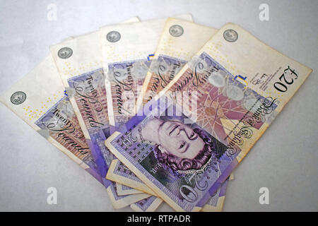 Un centinaio di stagni in venti pound note sparse su sfondo bianco Foto Stock