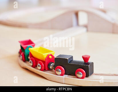 Giocattolo di legno di marcia del treno in miniatura su binari ferroviari. Il motore nero tirando le auto colorate sul pavimento. Giocattoli educativi per i bambini in età prescolare Foto Stock