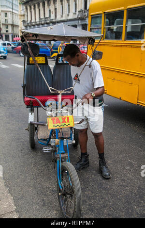 L'Avana, Cuba - 19 Gennaio 2013: una vista delle strade della città con il popolo cubano. Un uomo parcheggia la sua bicicletta taxi. Foto Stock