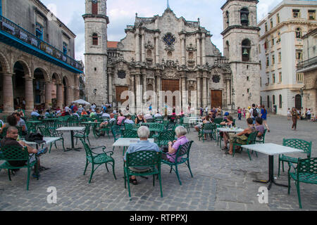 L'Avana, Cuba - 21 Gennaio 2013: una vista delle strade della città con il popolo cubano. Le persone al di fuori seduta in un bar di fronte alla cattedrale. Foto Stock