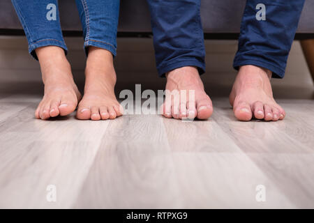 Sezione bassa del giovane con i piedi sul pavimento in soggiorno Foto Stock