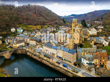 Scenic paesaggio autunnale del villaggio francese di Estaing sulla banca del fiume Lot con castello medievale e antica pietra ponte arcuato Foto Stock