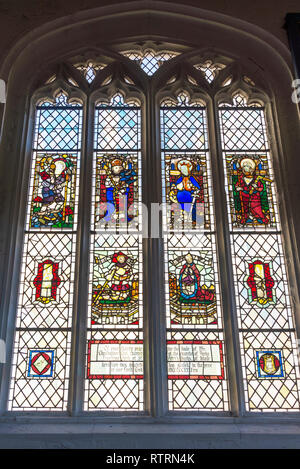 Vetrata di St Michael le Belfrey chiesa in York. Il vetro colorato raffigura i santi e un'iscrizione di seguito. Foto Stock