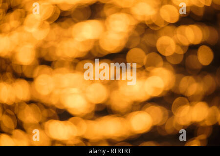 Luccicante e scintillante di giallo e arancione sfocata superficie dell'oceano al tramonto con sole riflessioni su di esso Foto Stock